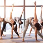 Multiethnische gruppe junger menschen, die yoga-übungen in einem modernen loft-studio durchführen