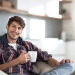 Junger mann mit einer tasse kaffee im hintergrund in der küche