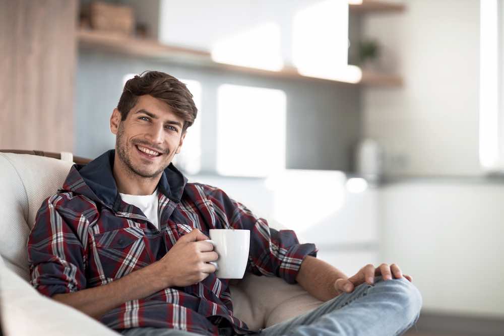 Junger mann mit einer tasse kaffee im hintergrund in der küche