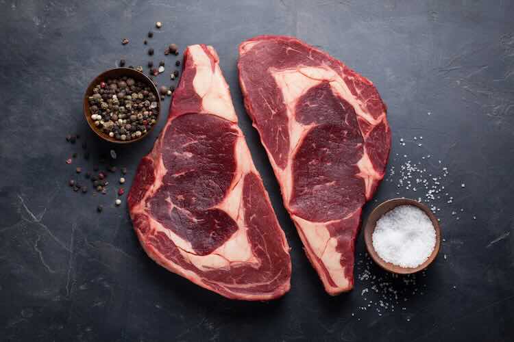 Rohes frisches marmoriertes Steak Steak Ribeye schwarzen Lachs auf schwarzem Marmorhintergrund . Rindfleisch mit Gewürzen auf einem dunklen Steintisch . Draufsicht
