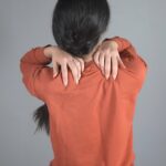 Frauenhand in schmerzender schulter auf grauem hintergrund
