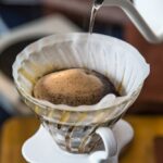 Nahaufnahme von filterkaffeemaschine, wasserkocher mit thermometer und digitalwaage auf holztisch. barista brüht kaffee, methode gießt über, tropft kaffee